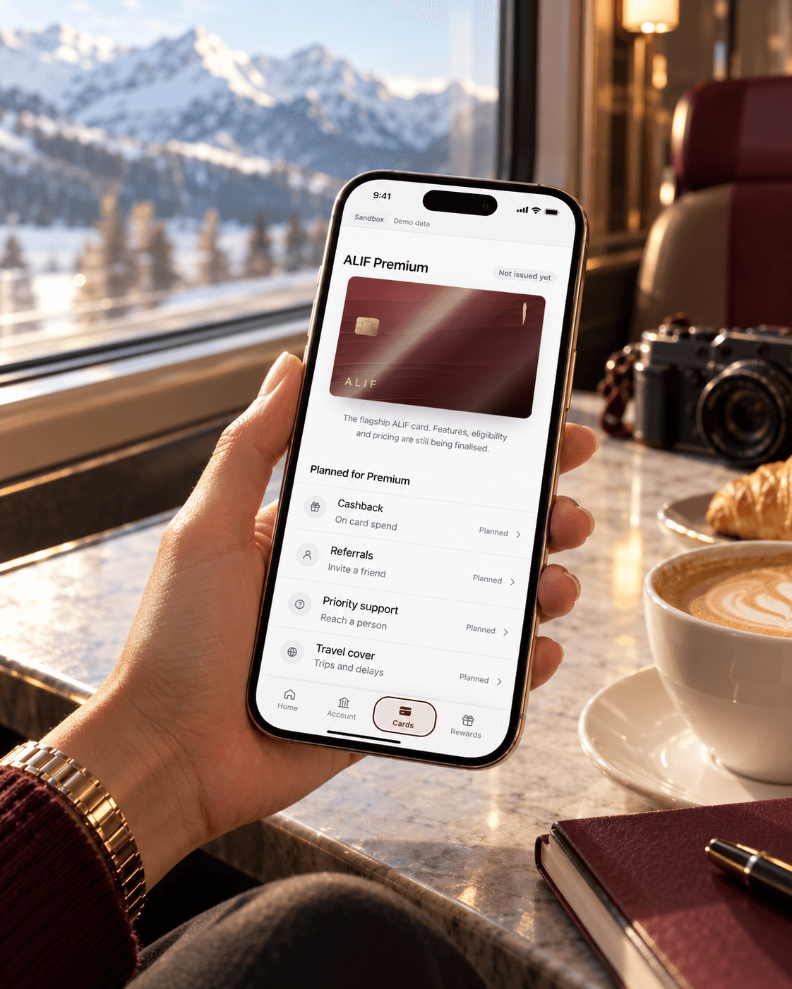 A phone held at a train window, open on the ALIF Premium screen in the app.